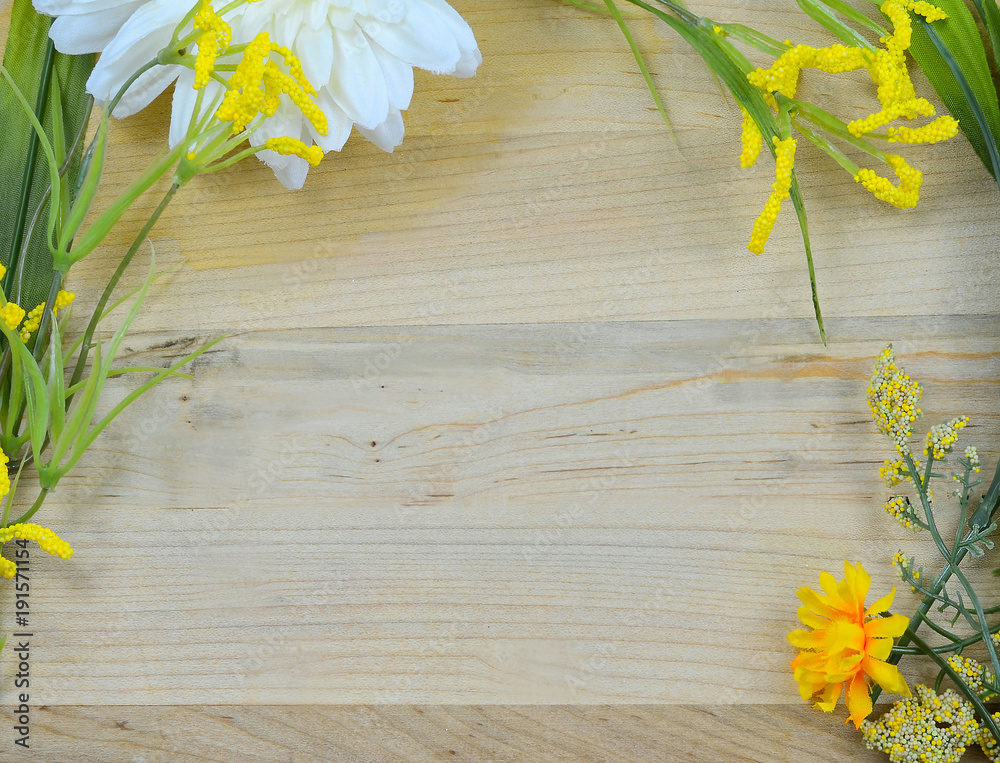 Obraz premium Spring border of artificial yellow flowers on rustic wooden background. Copy space for your message.