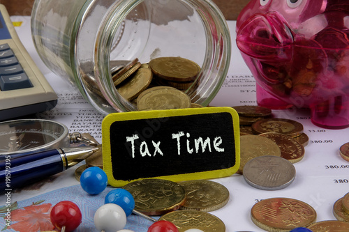 TAX CONCEPT. Coins,calculator,bank notes and wood plate on a white table. photo