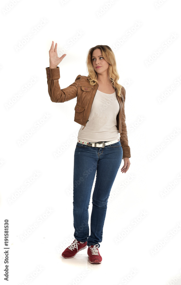 full length portrait of blonde girl wearing simple brown jacket and jeans, standing pose on white studio background. full length portrait of blonde girl wearing simple brown jacket and jeans, standing pose on white studio background.