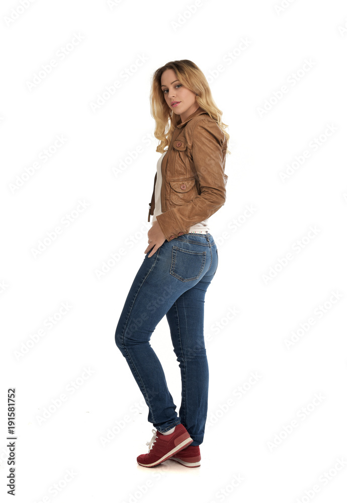 full length portrait of blonde girl wearing simple brown jacket and jeans, standing pose on white studio background. full length portrait of blonde girl wearing simple brown jacket and jeans, standing pose on white studio background.