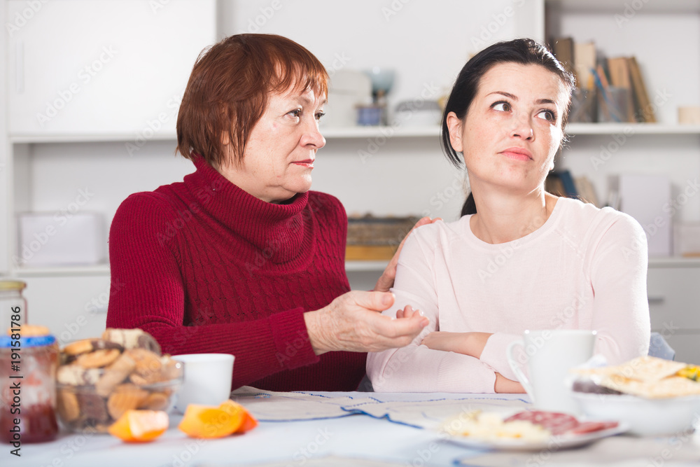 Portrait of sad mature woman talking with daughter