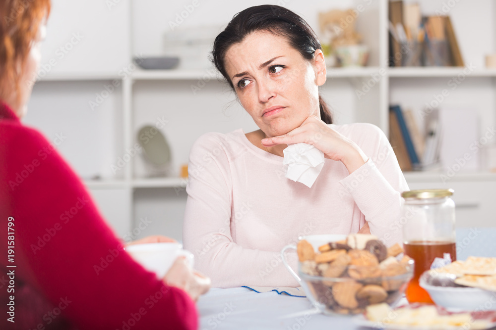 Unhappy female talking with mother at table