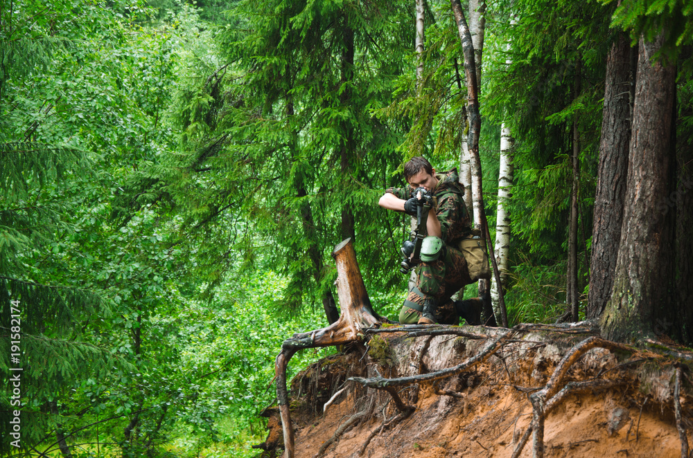 soldier aims and shoots standing in a fighting stand on a hill in the forest soldier aims and shoots standing in a fighting stand on a hill in the forest