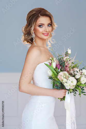 Portrait of a beautiful bride with a wedding bouquet. Blonde girl with curly hair and fashion makeup.