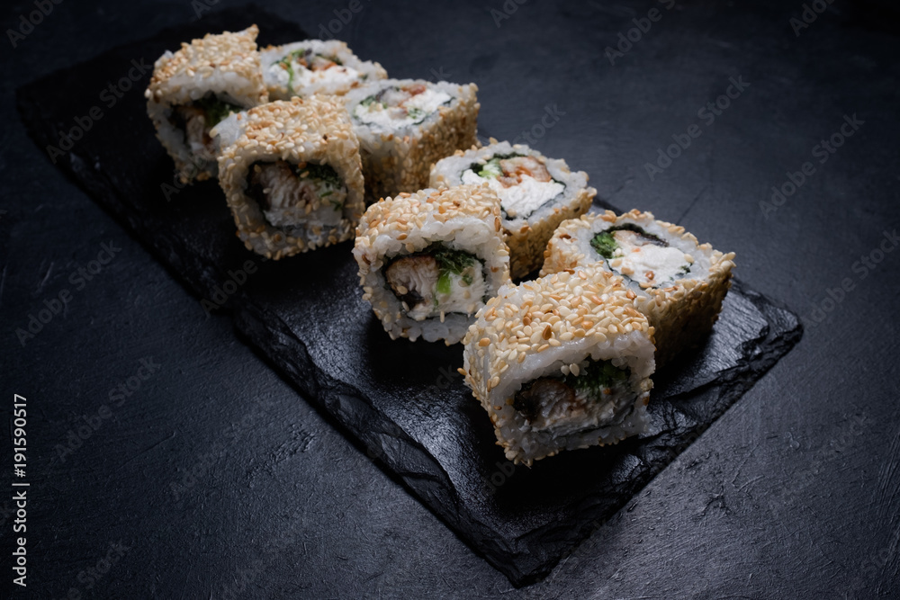 dragon eel sushi rolls in sesame seeds on dark background. Japanese cuisine restaurant menu. Delicious traditional eastern food dragon eel sushi rolls in sesame seeds on dark background. Japanese cuisine restaurant menu. Delicious traditional eastern food