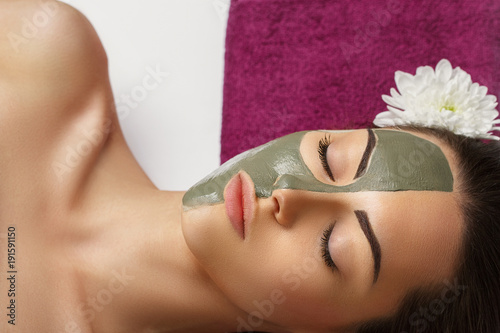 Woman with clay facial mask in beauty spa. Skincare. Beauty Concept. Close-up portrait of beautiful girl with facial mask.Facial treatment. Cosmetology. Body care girl's