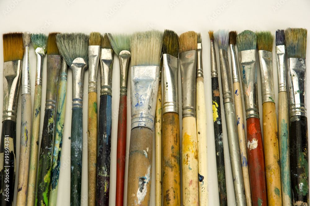 Obraz premium Well used artists paintbrushes on a white paper background