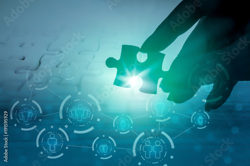 Photos hand holding jigsaw piece with background of teamwork people connection