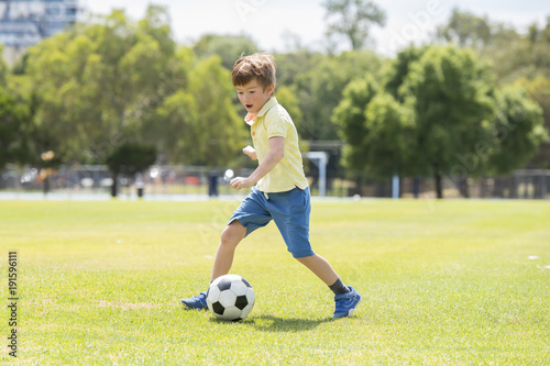 Canvas Print little kid 7 or 8 years old enjoying happy playing football soccer at grass city
