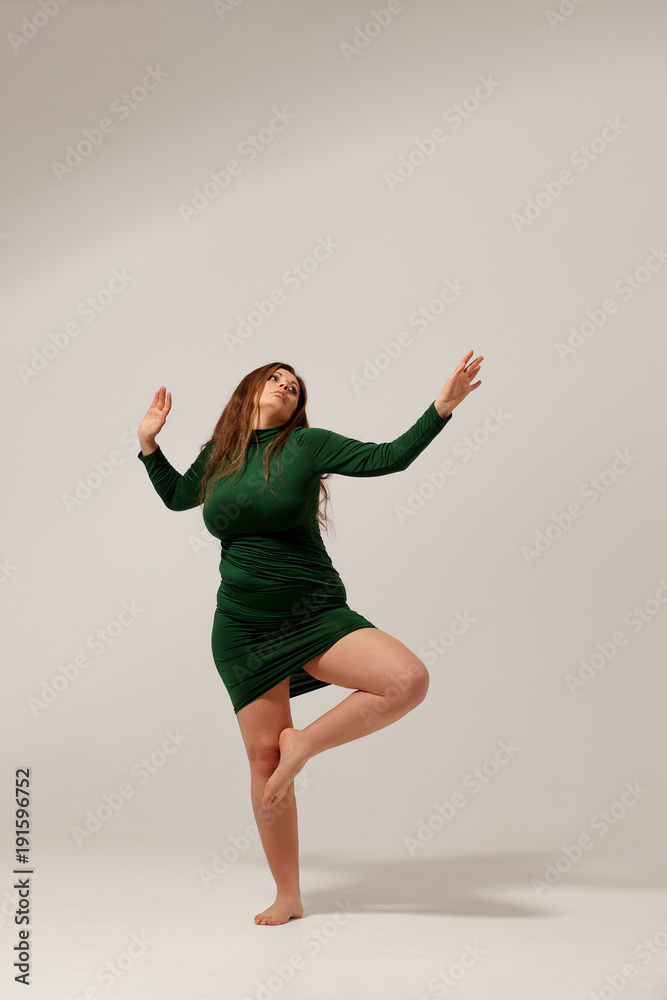 Obese woman in green dress standing on one foot. Isolated on white background. Obese woman in green dress standing on one foot. Isolated on white background.