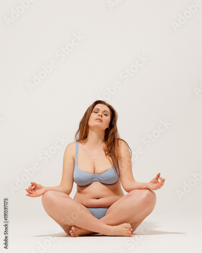 Beautiful girl in underwear sitting on floor and meditating. © Svyatoslav Lypynskyy