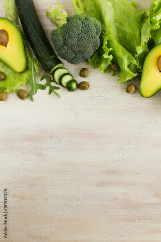 Green vegetables, fruit, and arugula salad on a light background