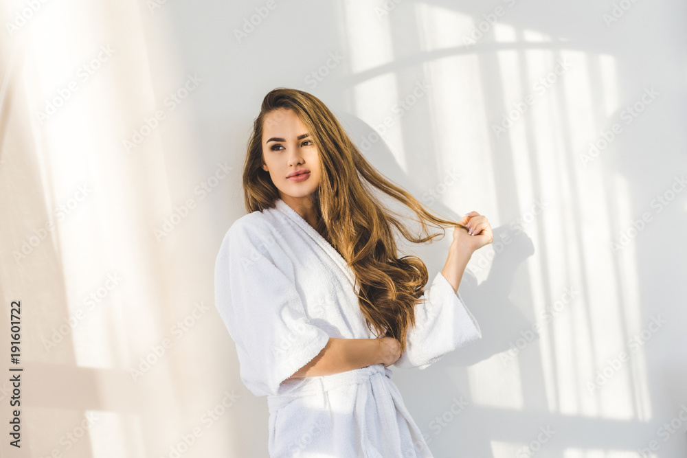 portrait of pretty young woman in bathrobe leaning on white wall at home portrait of pretty young woman in bathrobe leaning on white wall at home