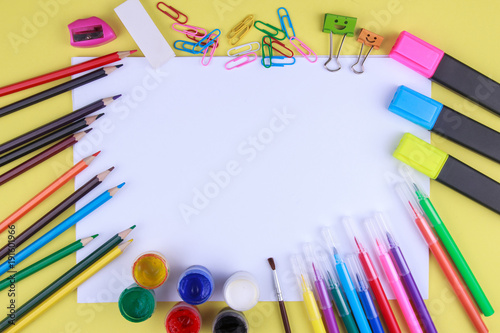 paper with colored crayons, brush, pencils and paints on yellow background. Top view . Flat lay image.Working desk table concept.