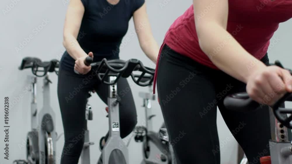 Two women are on cardio training in sports club indoors. Sportive partners are moving on aerobic machines in modern studio. Fitness ladies are practiced actively, special mechanics of movements work Two women are on cardio training in sports club indoors. Sportive partners are moving on aerobic machines in modern studio. Fitness ladies are practiced actively, special mechanics of movements work