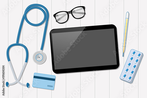 Doctor office with tablet and stethoscope on white wood table.
