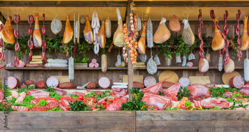 fresh food market background with raw pork and vertical assorted salami sausages.
