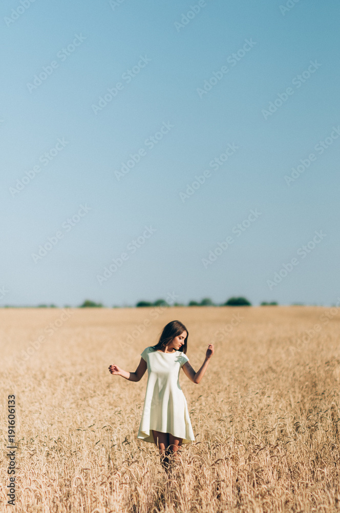 A girl in a white dress in the middle of a wheat field A girl in a white dress in the middle of a wheat field