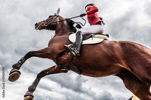 Fotografie A horse with a rider jumps over an obstacle