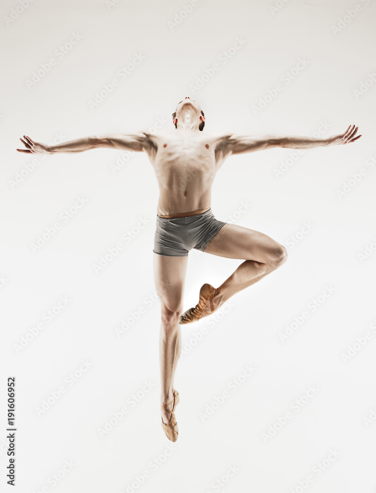 Athletic ballet dancer in a perfect shape performing over the grey background. Athletic ballet dancer in a perfect shape performing over the grey background.