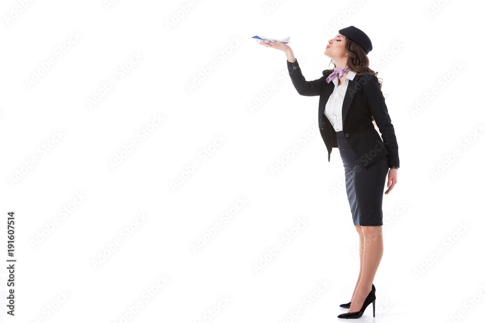 side view of attractive stewardess blowing at plane toy isolated on white side view of attractive stewardess blowing at plane toy isolated on white