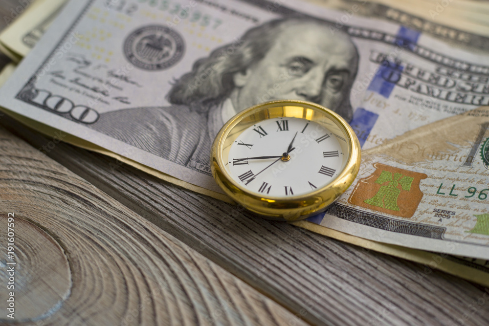 United States paper money on the table next to clock. USA dollars. Money concept. Closeup United States paper money on the table next to clock. USA dollars. Money concept. Closeup