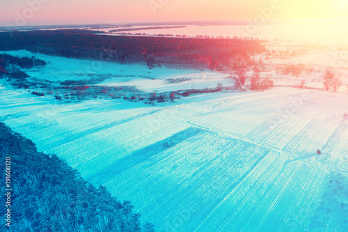 Rural winter landscape. Aerial view. Field covered with snow and forest