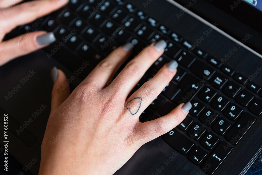 Female Hand with Heart Tattoo Using Laptop Keyboard Female Hand with Heart Tattoo Using Laptop Keyboard