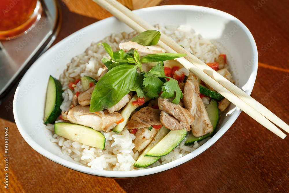 Asian riсe with pork and vegetables in oval plate with bamboo sticks Asian riсe with pork and vegetables in oval plate with bamboo sticks