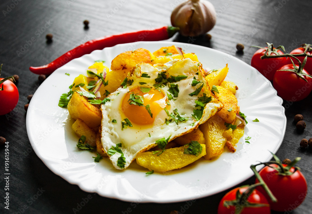 fried egg with potato in a plate on dark wooden background