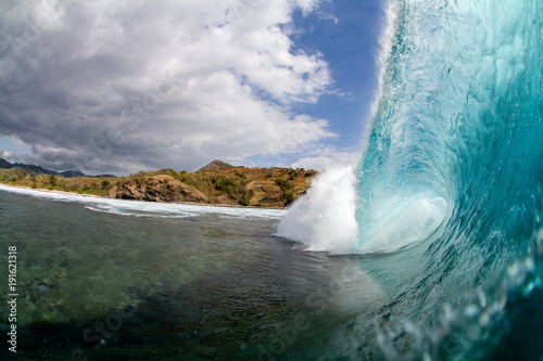 wave breaking over a shallow coral reef on a tropical island in indonesia