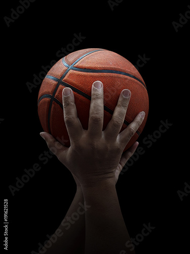 Basketball player holding a ball against black background © Retouch man