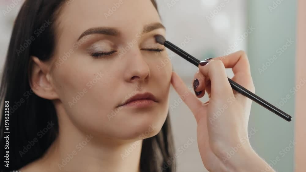 Woman putting eye shadows brush artist red lipstick looking in mirror. Makeup at night getting ready before going to party. Woman putting eye shadows brush artist red lipstick looking in mirror. Makeup at night getting ready before going to party.