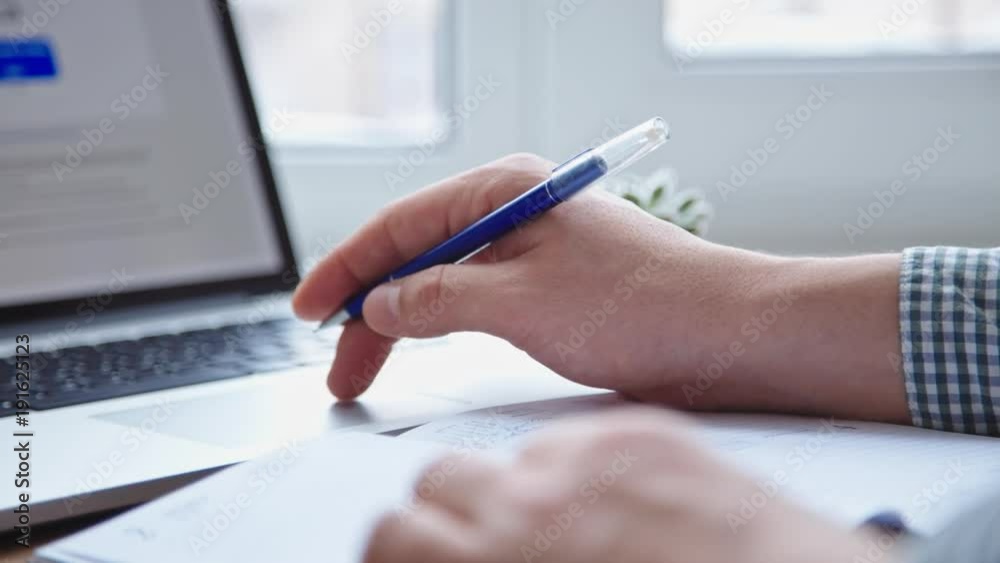 Top view of man working on laptop placed on wooden desk