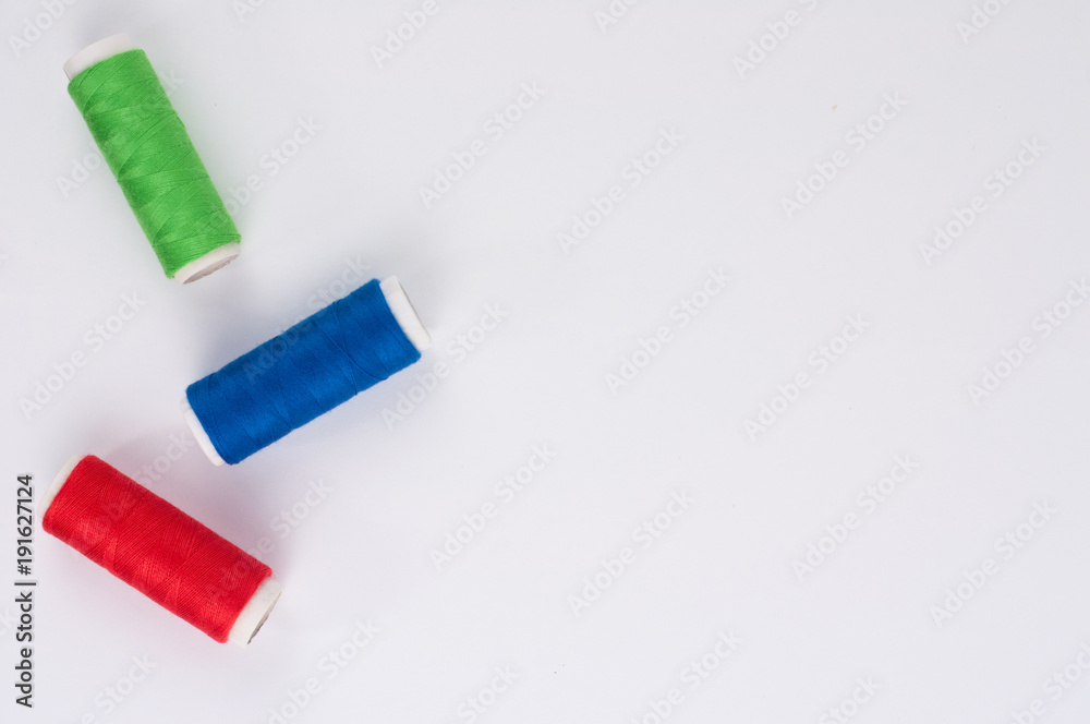 Three bobbin of new colorful thread on white background. Top view Three bobbin of new colorful thread on white background. Top view
