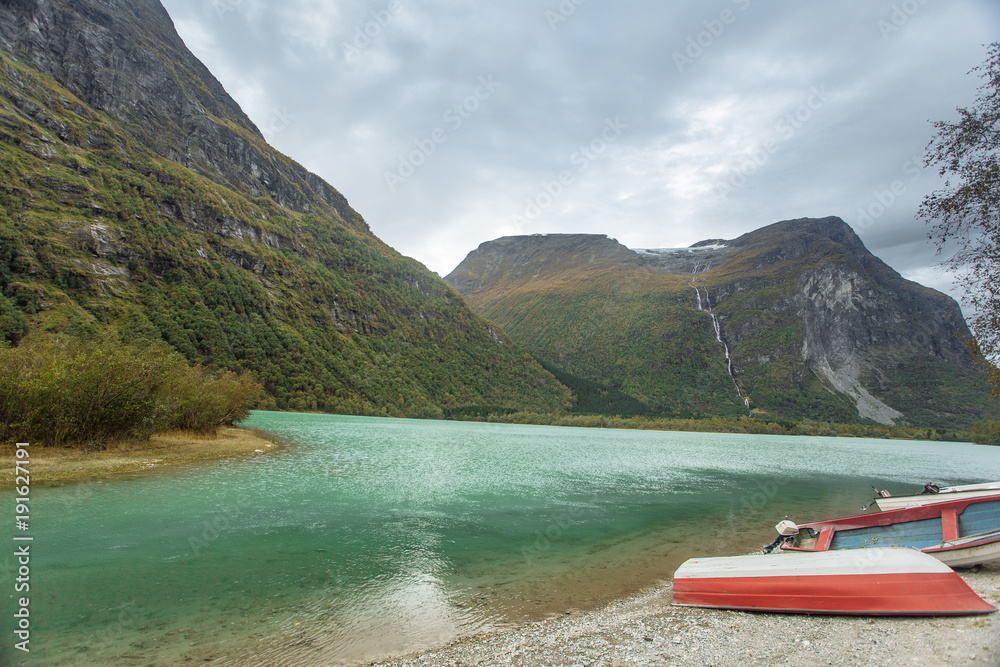 Red boat on the shore with view to mountains in the Norway