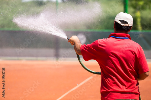 Preparation of a tennis court watering from a hose photo