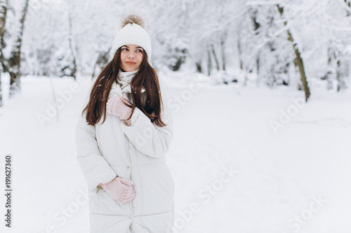 A beautiful and fashoin woman in white warm clothing walking in snowy weather.