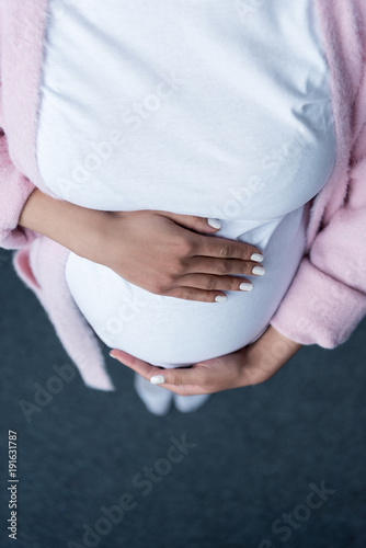 partial view of pregnant woman touching her belly