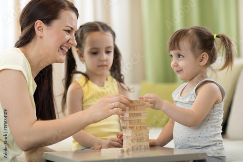 mother and her little daughters are playing with board game