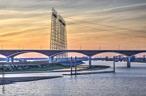 Evening view of city bridge De Oversteek (The Crossing) and electicity lines crossing the newly created channel of the river Waal near Nijmegen, The Netherlands photo