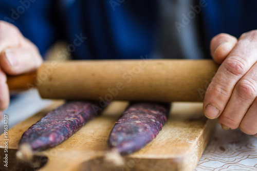 Slika na platnu Closeup of man hands rolling over homemade sausages to make them flat for drying