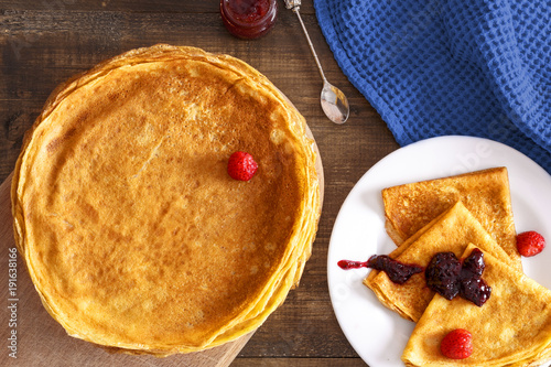 Thin pancakes on a table and on a plate top view
