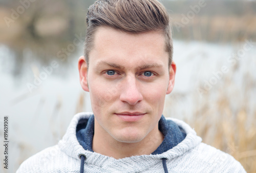 handsome blond man in front of lake