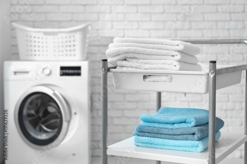 Stack of clean towels on cart in laundromat © Africa Studio