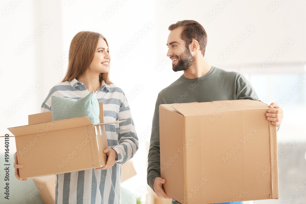 Young couple with moving boxes in room at new home Young couple with moving boxes in room at new home