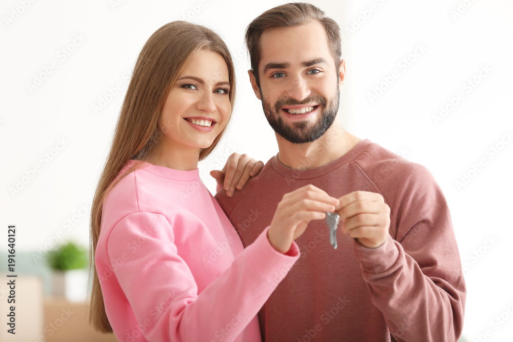Happy owners holding keys of their new house, indoors Happy owners holding keys of their new house, indoors
