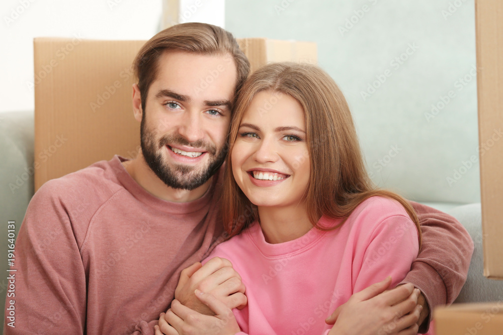 Young couple with moving boxes in room at new home Young couple with moving boxes in room at new home
