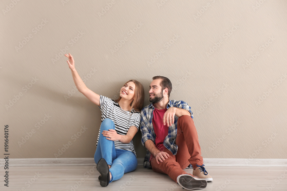 Fotografie Young couple sitting on floor in empty room