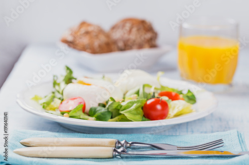 Poached egg with green salad, tomatoes, wholemeal bread and orange juice